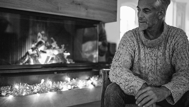 senior man sitting by a fireplace