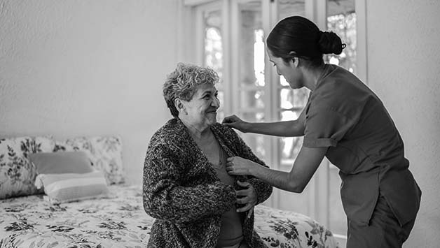 aide helping senior woman get dressed