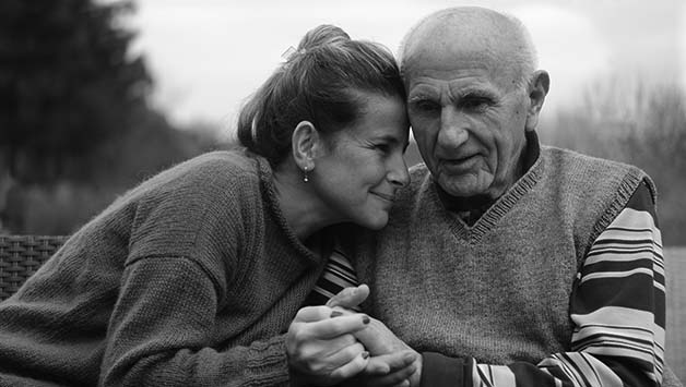 adult daughter cuddles senior father