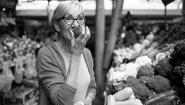 woman smelling tomato at market